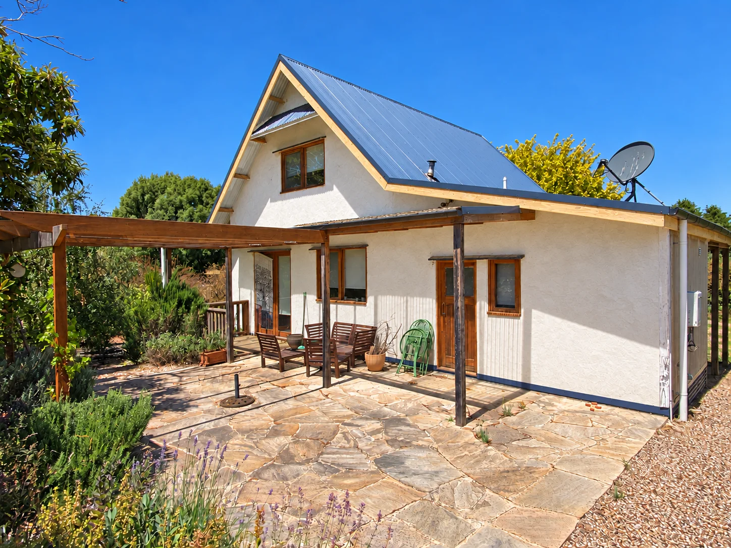 Recent view of the Daylesford light-earth house with rendered walls, timber fascias and a garden courtyard