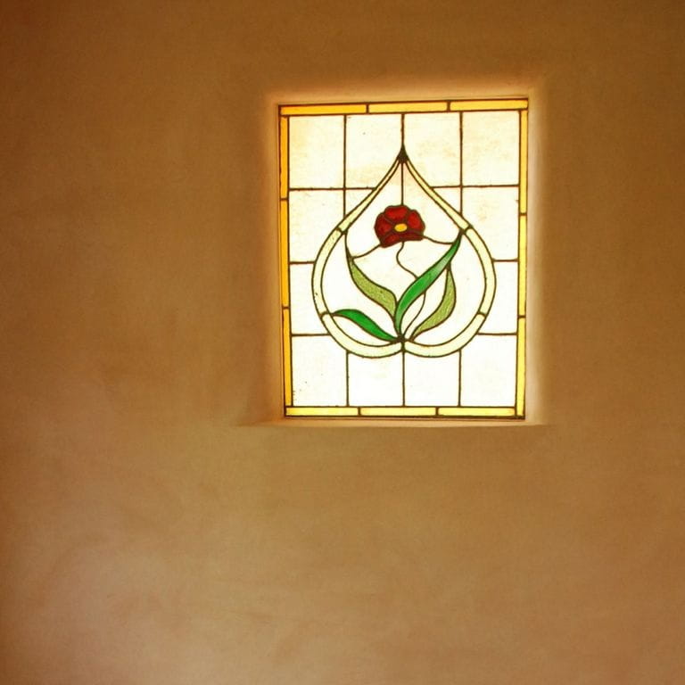 Decorative stained-glass window set in the earth-rendered interior wall